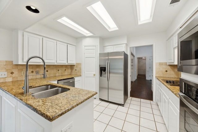 kitchen featuring stainless steel appliances, sink, backsplash, light tile patterned floors, and white cabinetry