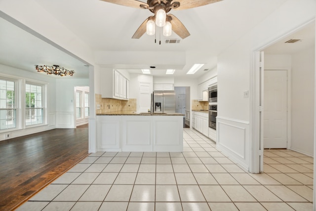 kitchen featuring light hardwood / wood-style flooring, white cabinets, ceiling fan, stainless steel appliances, and decorative backsplash