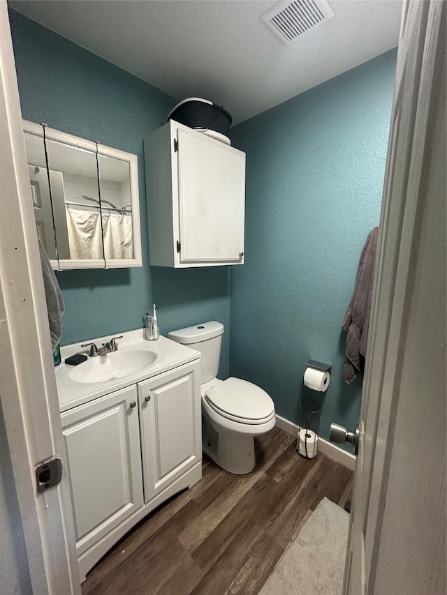 bathroom featuring toilet, hardwood / wood-style floors, and vanity