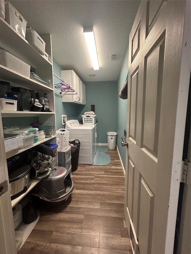 washroom with a textured ceiling, dark hardwood / wood-style flooring, cabinets, and separate washer and dryer