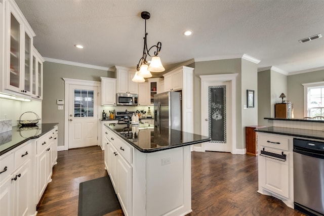 kitchen featuring hanging light fixtures, white cabinets, stainless steel appliances, and a kitchen island