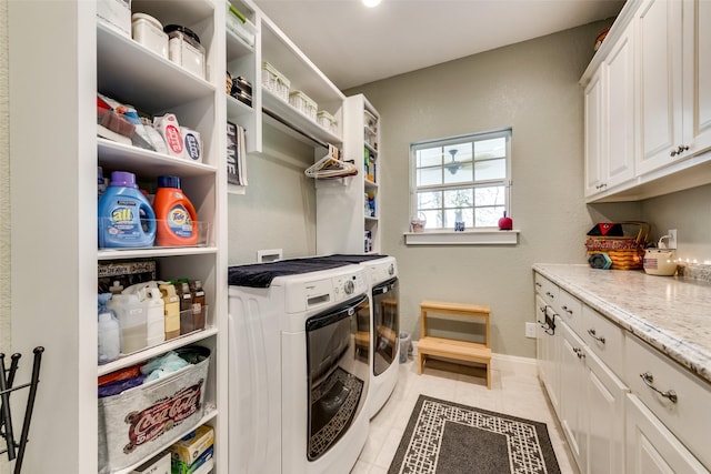 laundry room featuring cabinets, light tile patterned floors, and washer and clothes dryer