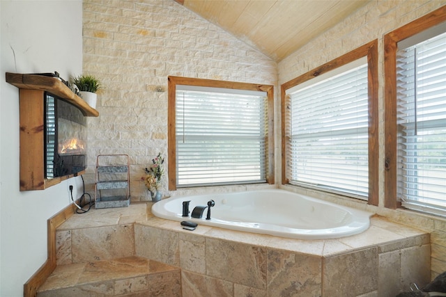 bathroom with tiled tub and vaulted ceiling