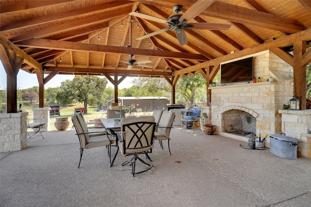 view of patio with an outdoor stone fireplace, ceiling fan, and a gazebo