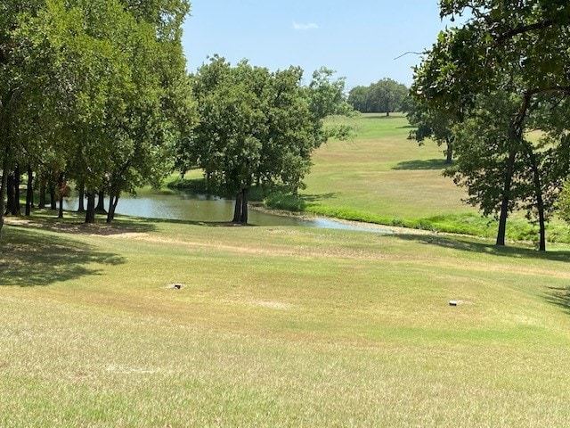 surrounding community featuring a water view and a lawn