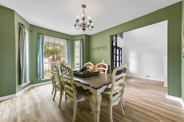 dining room with light wood-type flooring and a notable chandelier