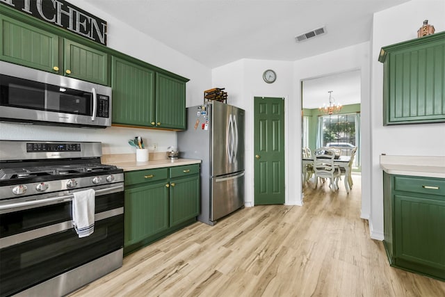 kitchen featuring appliances with stainless steel finishes, light wood-type flooring, green cabinetry, and a notable chandelier