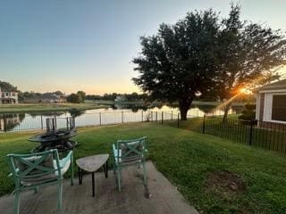 yard at dusk with a water view and a patio area