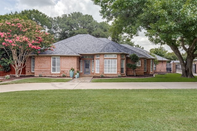 single story home with roof with shingles, a chimney, a front lawn, and brick siding