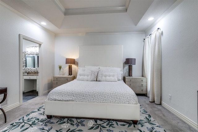 carpeted bedroom featuring a raised ceiling, crown molding, and ensuite bath