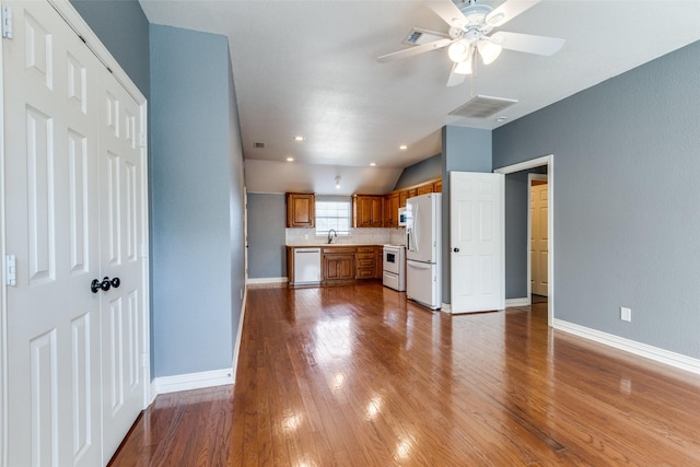 kitchen with sink, white appliances, ceiling fan, light hardwood / wood-style floors, and backsplash