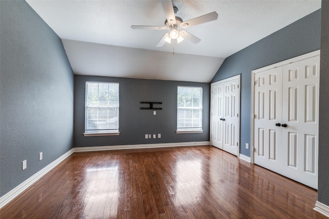 unfurnished bedroom featuring lofted ceiling, multiple closets, multiple windows, and ceiling fan