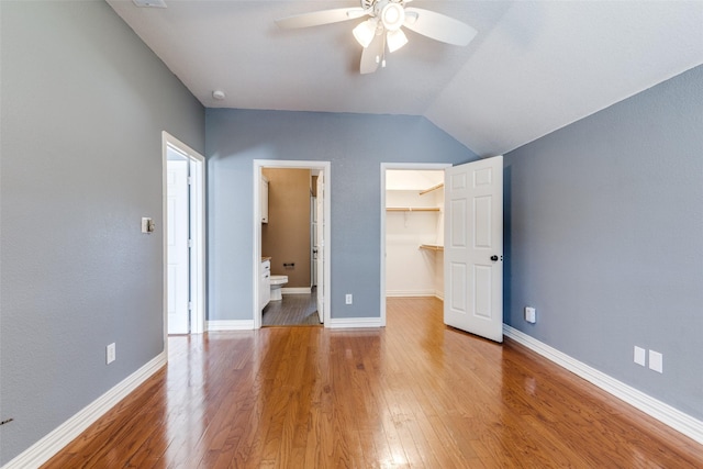 unfurnished bedroom with a closet, a walk in closet, ceiling fan, and light hardwood / wood-style floors