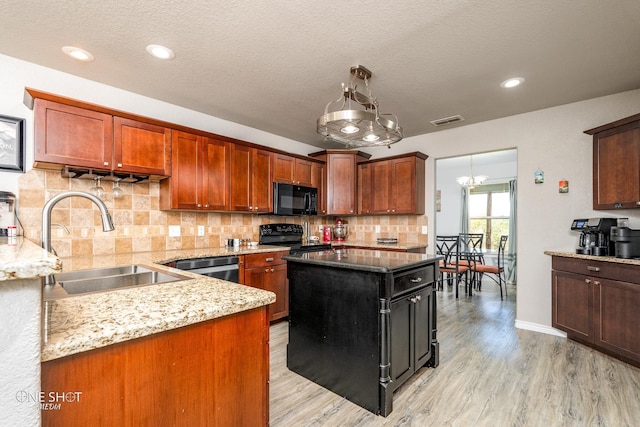 kitchen featuring light stone countertops, black appliances, a kitchen island, light hardwood / wood-style floors, and sink