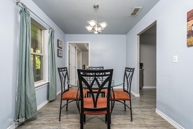 dining area with hardwood / wood-style floors, a textured ceiling, and a chandelier