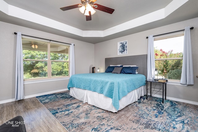 bedroom featuring ceiling fan, hardwood / wood-style floors, and a tray ceiling