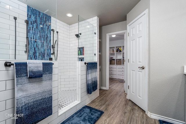 bathroom with a textured ceiling, hardwood / wood-style floors, and tiled shower