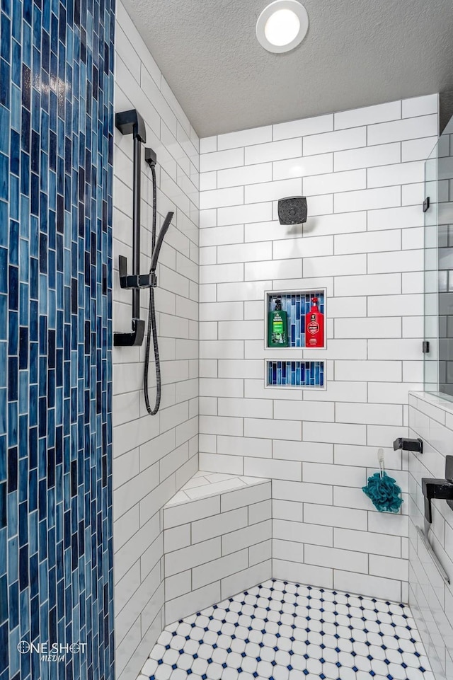 bathroom featuring a textured ceiling and tiled shower