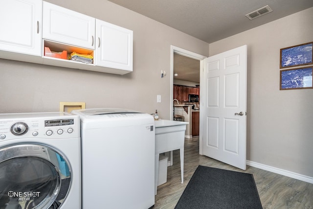 laundry room with hardwood / wood-style flooring, cabinets, and washer and clothes dryer