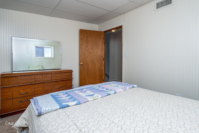 bedroom with carpet floors, a paneled ceiling, and wood walls