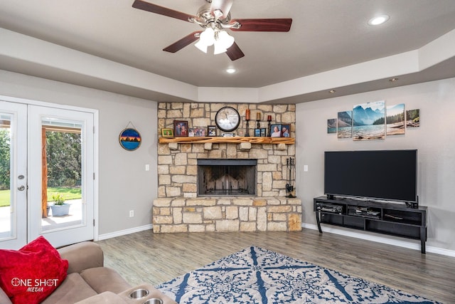 living room featuring ceiling fan, hardwood / wood-style floors, french doors, and a fireplace