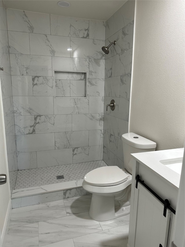 bathroom featuring toilet, a tile shower, vanity, and tile patterned flooring