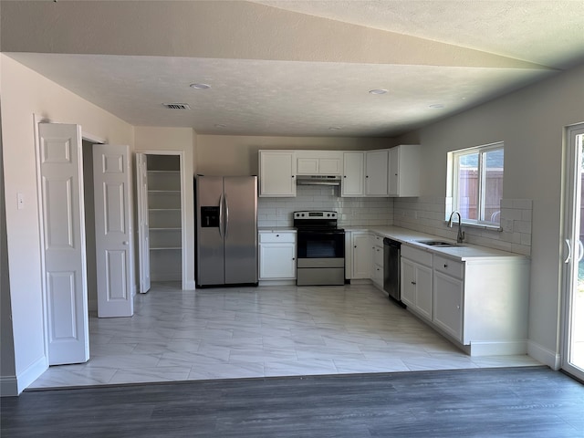 kitchen featuring backsplash, appliances with stainless steel finishes, light tile patterned floors, and white cabinetry