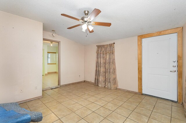 empty room with a textured ceiling, ceiling fan, and light tile patterned floors