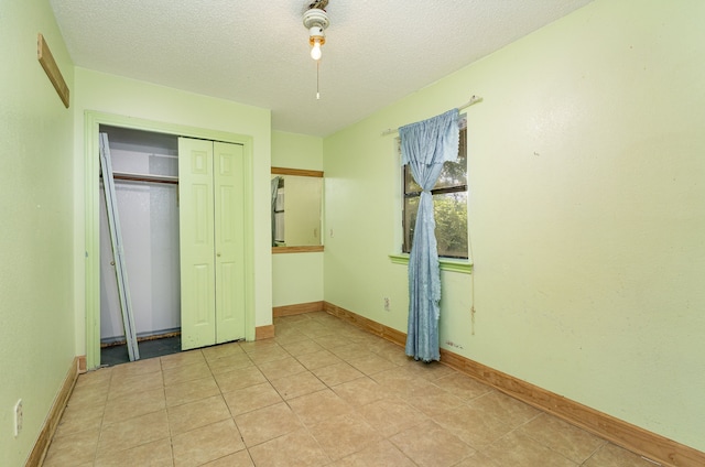 unfurnished bedroom featuring a textured ceiling, a closet, and light tile patterned floors