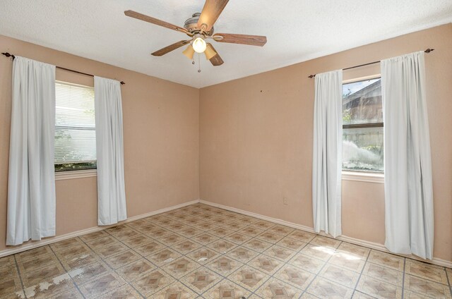 spare room with a textured ceiling, light tile patterned floors, and ceiling fan