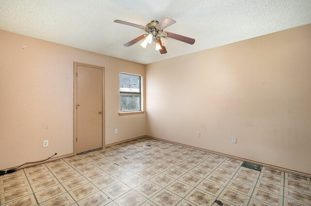 tiled spare room with a textured ceiling and ceiling fan