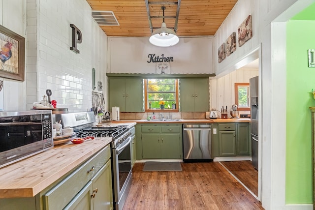 kitchen with butcher block countertops, wood ceiling, appliances with stainless steel finishes, green cabinets, and hardwood / wood-style flooring