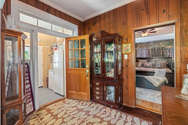 interior space with ornamental molding, ceiling fan, and wood walls