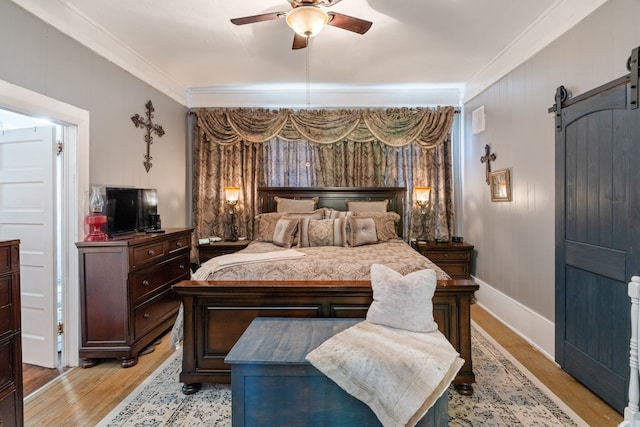 bedroom with crown molding, ceiling fan, a barn door, and light wood-type flooring