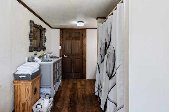 washroom with crown molding, dark wood-type flooring, sink, and a textured ceiling