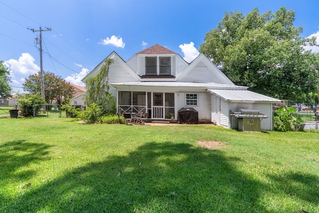 rear view of house with a sunroom and a lawn