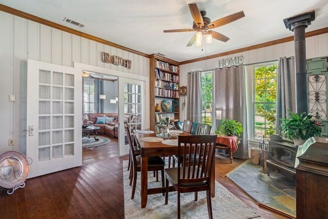 dining space featuring dark hardwood / wood-style floors, ornamental molding, french doors, and a wood stove