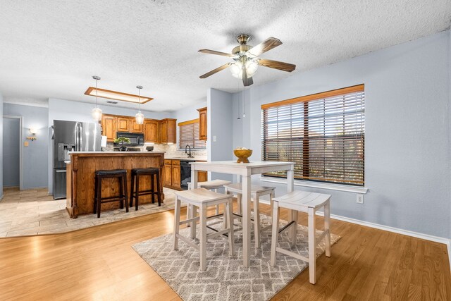 dining area with a textured ceiling, ceiling fan, and light hardwood / wood-style floors