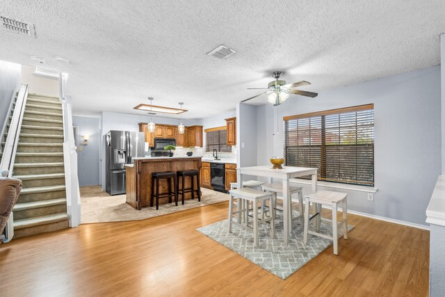 dining area featuring a textured ceiling, ceiling fan, light hardwood / wood-style floors, and sink