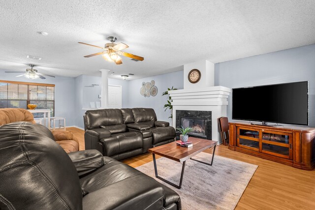 living room featuring a high end fireplace, a textured ceiling, and light hardwood / wood-style floors