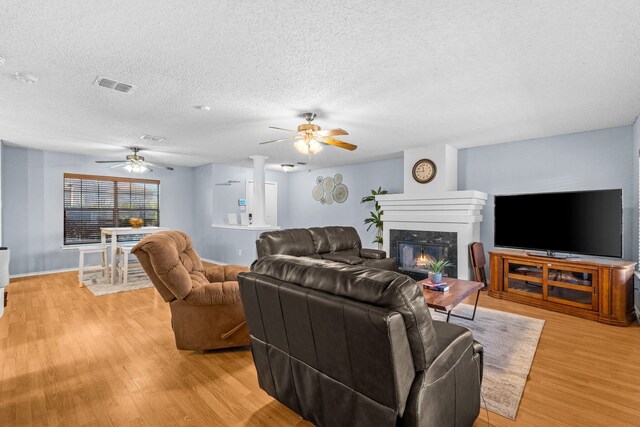 living room featuring a textured ceiling, light hardwood / wood-style flooring, and a premium fireplace