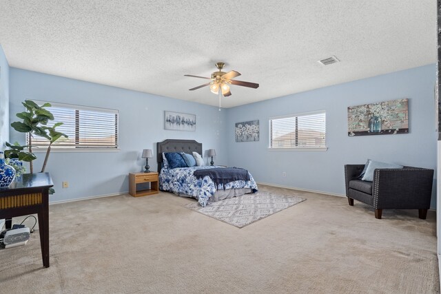 bedroom with a textured ceiling, ceiling fan, and light carpet