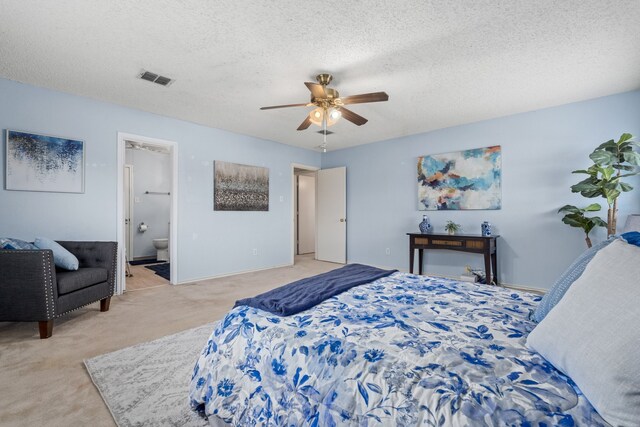 bedroom featuring ceiling fan, light colored carpet, a textured ceiling, and ensuite bathroom