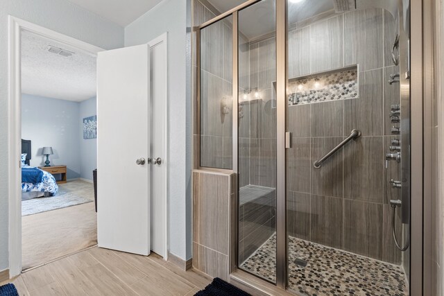 bathroom with hardwood / wood-style flooring, a textured ceiling, and walk in shower