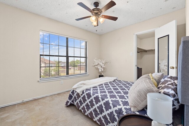 bedroom with ceiling fan, a textured ceiling, a closet, and a walk in closet