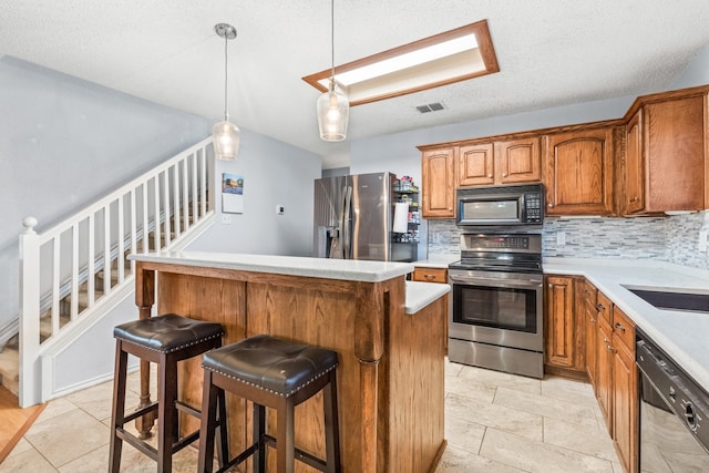 kitchen with black appliances, a center island, backsplash, hanging light fixtures, and a breakfast bar area