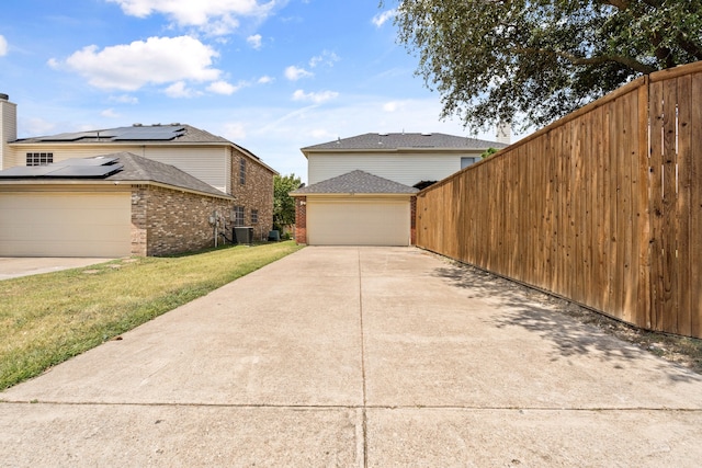 view of home's exterior featuring a garage, cooling unit, and a lawn