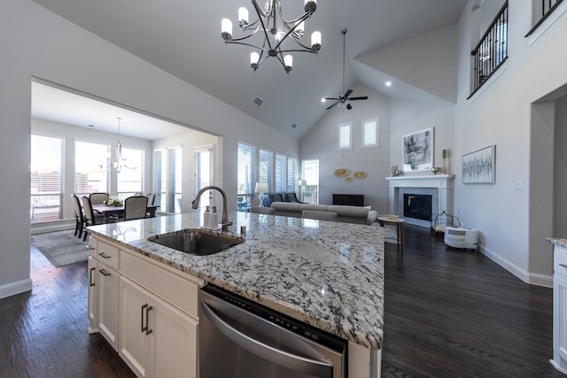 kitchen with pendant lighting, sink, dishwasher, white cabinetry, and light stone countertops