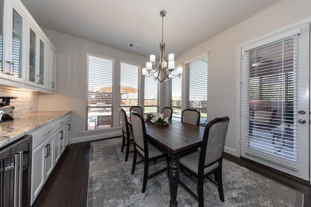 dining room featuring dark wood-type flooring, beverage cooler, and a chandelier