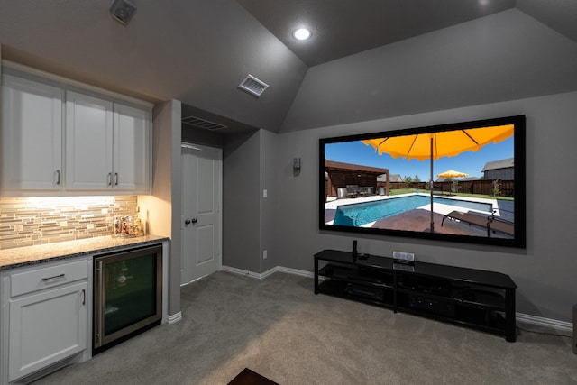 cinema room featuring lofted ceiling, carpet floors, beverage cooler, and bar area